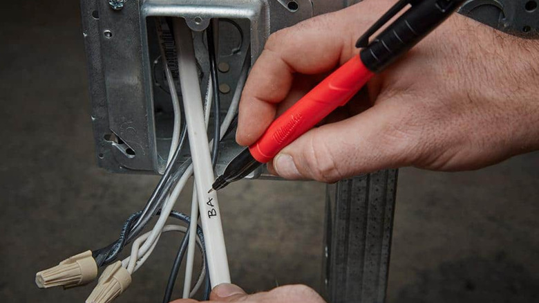 A person uses a Milwaukee Inkzall Jobsite Permanent Marker to write on cables.