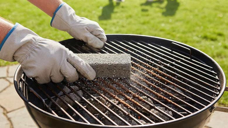 A person using a Pumie Pumice Scouring Stick on a grill in a garden.