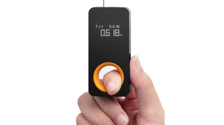 Stock photo of hand holding a black measuring device with a laser beam at the top
