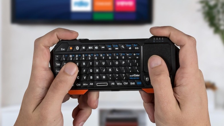 Hands holding a min keyboard resembling a video game controller