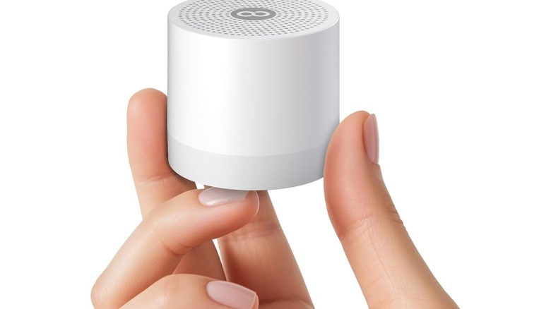 Stock photo of hand holding a white cylindrical speaker