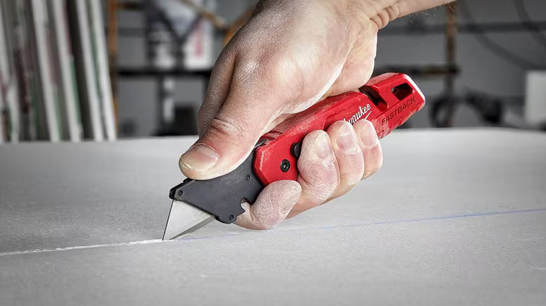 Man cutting material with a Milwaukee folding utility knife