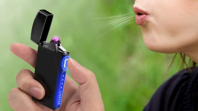 A woman blowing onto the iLevar Dual Arc Lighter to demonstrate its wind resistance.