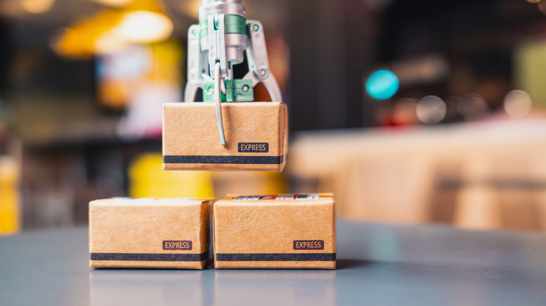 A robotic arm picking up a tiny parcel box.