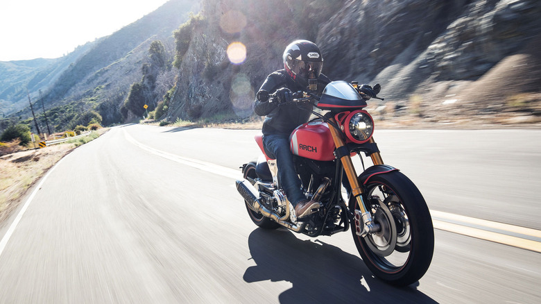 Person riding an Arch KRGT-1 motorcycle on a highway in a mountainous area