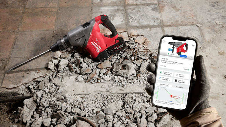 A Milwaukee rotary hammer with smartphone showing One-Key app
