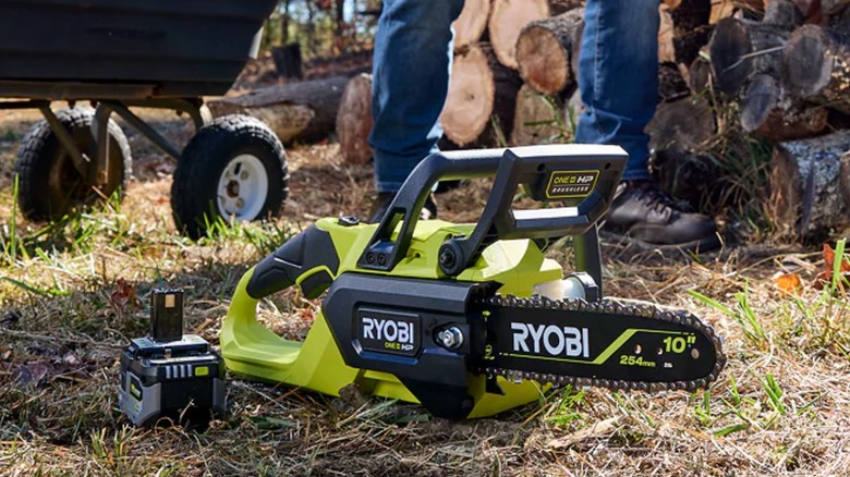 Ryobi chainsaw near a pile of logs