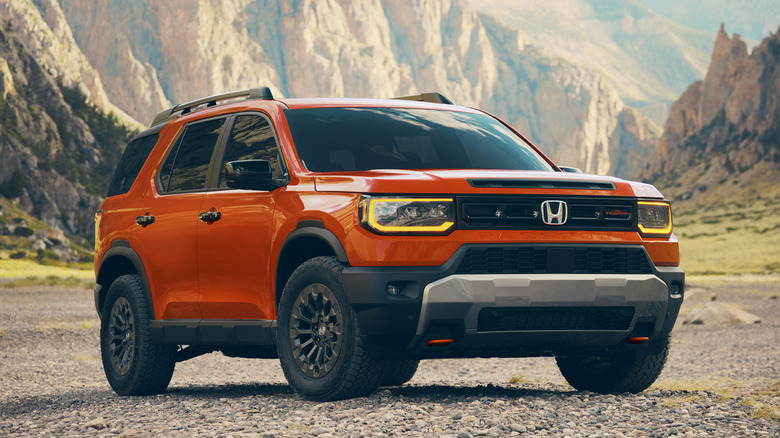 Orange Honda Passport parked on gravel with mountains in the background