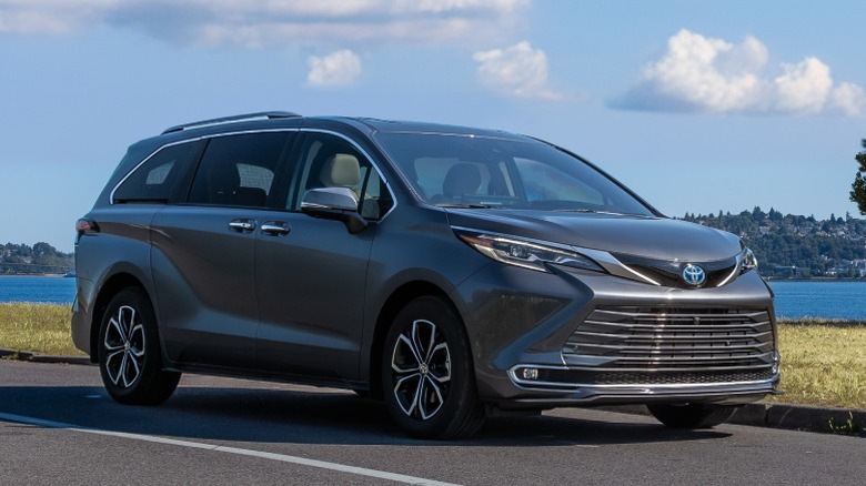 Gray Toyota Sienna parked on a road with a lake in the background