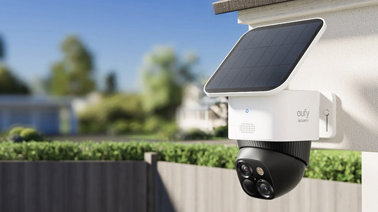 Eufy security camera and solar panel set up on the corner of a roof overlooking a yard.