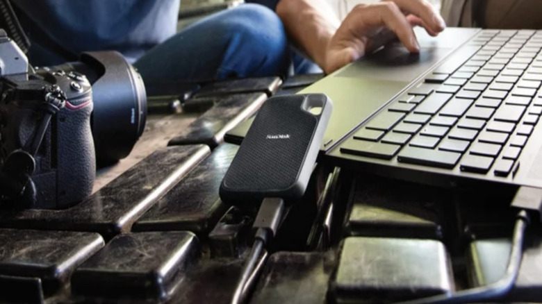 SanDisk portable SSD on a desk next to a computer keyboard and digital camera.