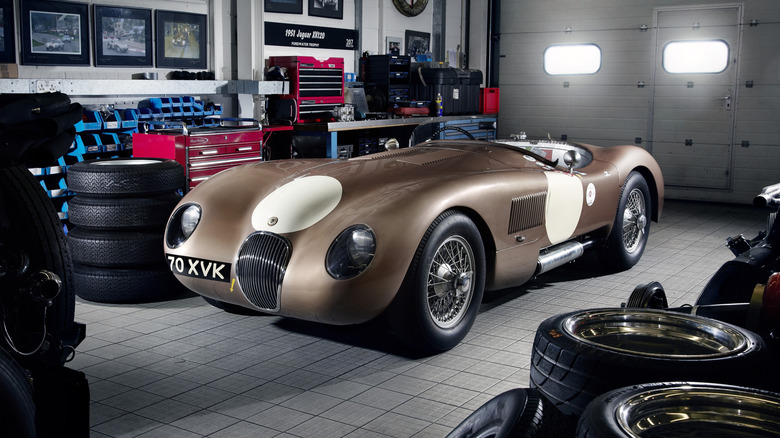 A brown Jaguar C-Type in a garage.