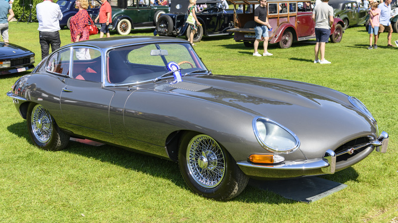Jaguar E-Type Series I on a yard surroudned by people.