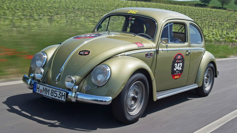 a green Volkswagen Beetle driving down the road