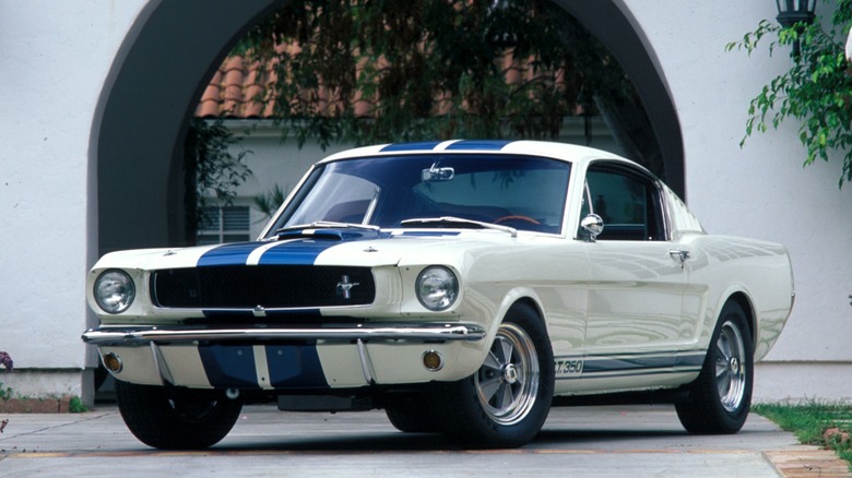 a white 1965 Ford Mustang with blue racing stripes