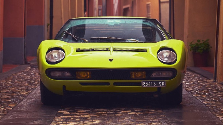 a yellow-green Lamborghini Miura in a cobblestone alley