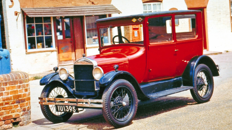 A red Ford Model T parked on the side of the road.