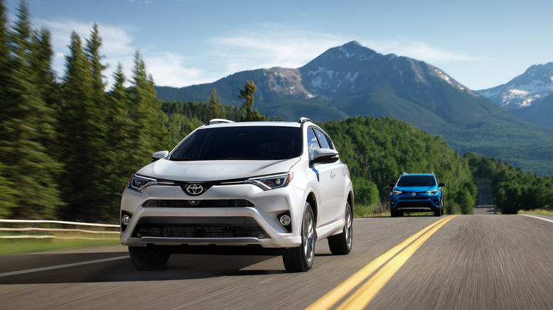 White and blue 2018 Toyota RAV4 Hybrids driving on a mountain road.