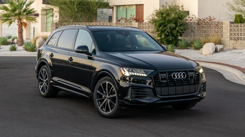 A black 2020 Audi Q7 luxury SUV driving through a desert neighborhood.