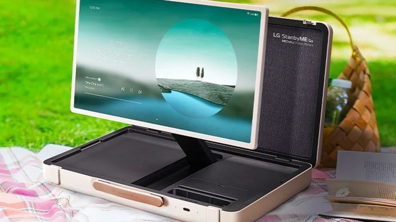 An LG StanbyME Go on a blanket with a book and picnic basket.