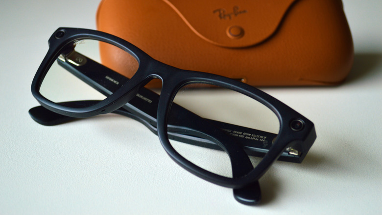 Some Meta smart glasses next to their case on a white surface