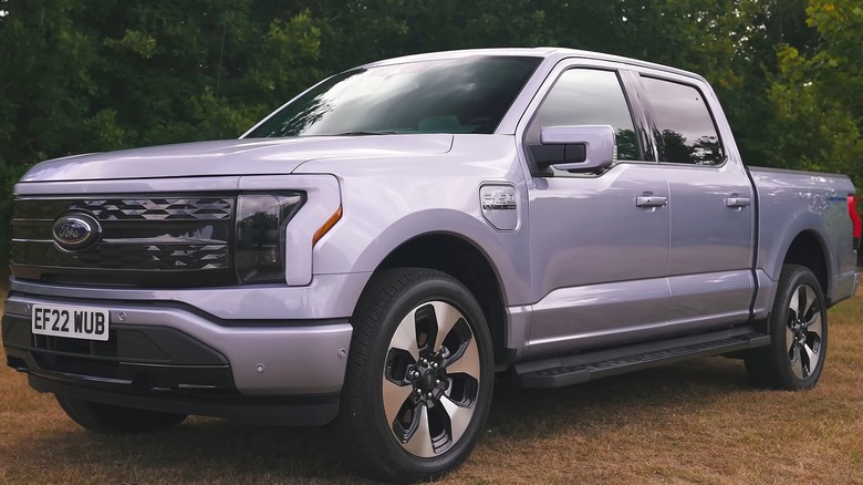 A silver Ford F-150 Lightning crew cab parked on a dry grass field.
