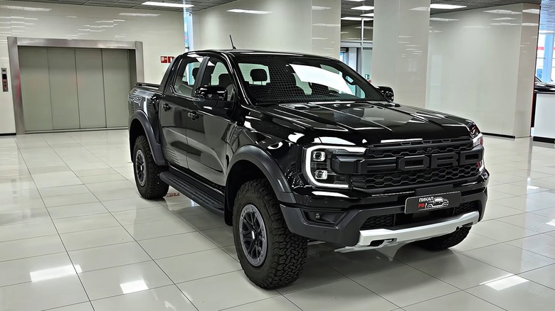 A jet black 2027 Ford Ranger Raptor placed in a showroom floor inside a dealership.
