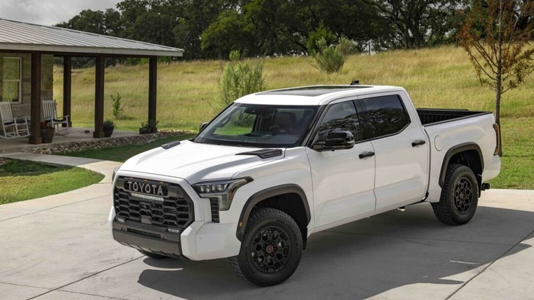 A white 2024 Toyota Tundra TRD Pro i-Force Max crew cab sitted on a residential driveway in a suburban neighborhood.