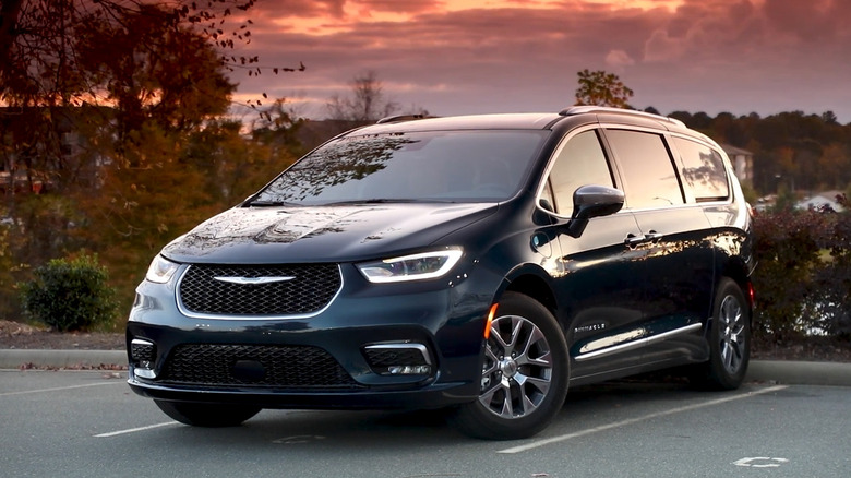 A dark blue Chrysler Pacifica Hybrid from 2023 standing against a dusky sky.