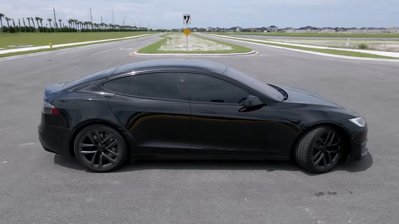 A black 2021 Tesla Model S standing on a paved road.