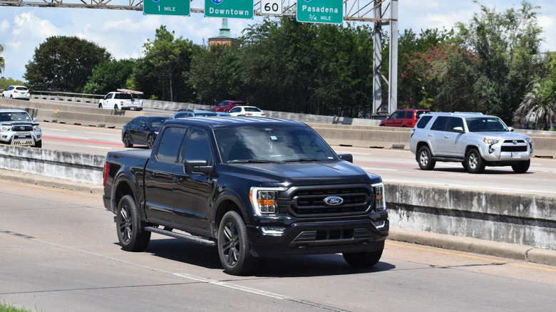A 2022 Ford F-150 Lightning electrified pickup truck moving down a city road.