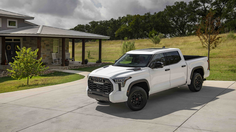 A white 2022 Toyota Tundra TRD Pro trim, parked next to a house in a field.