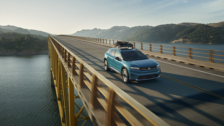 Blue Honda Prologue 2024 with roof rack moving down a bridge.