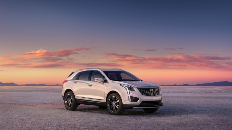 A 2025 Cadillac XT5 SUV on barren land against the setting sun.