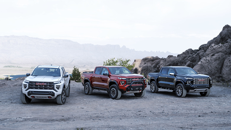 2025 GMC Canyon AT4, AT4X Edition 1, and Denali (left to right) standing on a mountain.