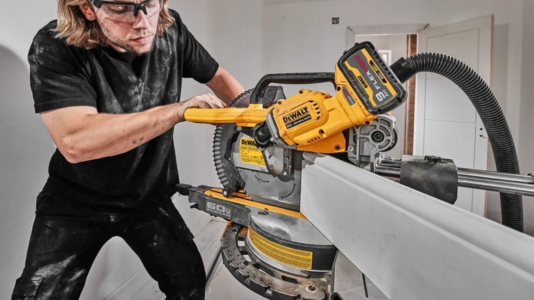 Man using DeWalt DCS781B Sliding Miter Saw on baseboard