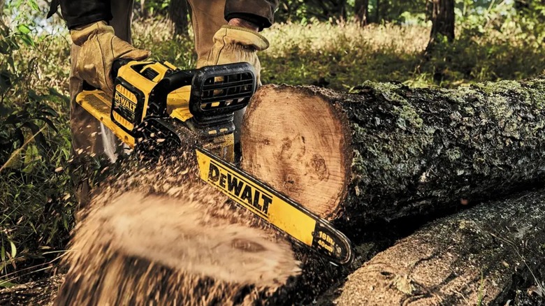 Person using DeWalt DCCS670B Chainsaw to chop tree