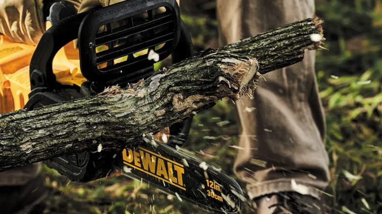 Person using DeWalt Chainsaw to chop branch