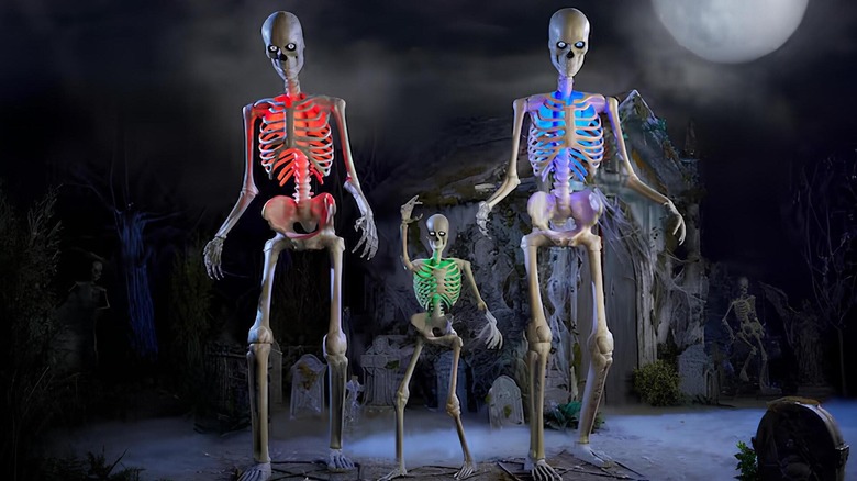 Three giant skeletons on a spooky porch under the moonlight