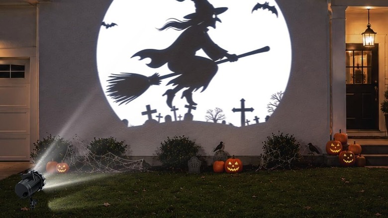 Halloween projector light projecting flying witch on garage door