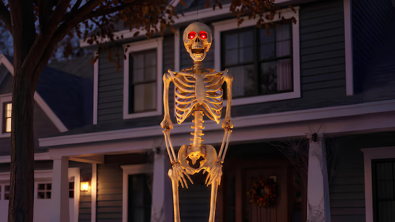 Skeleton with glowing red eyes standing outside a house
