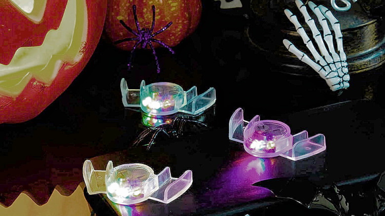 The Civaner Flashing LED Mouth Guards glowing next to some Halloween props.