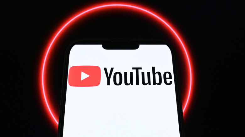 A smartphone showing the YouTube logo with a red ring in the background.