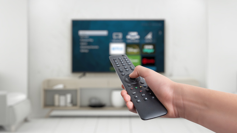 A person using a TV remote pointed at a TV