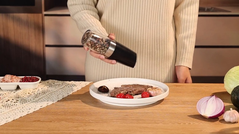 Person using pepper grinder