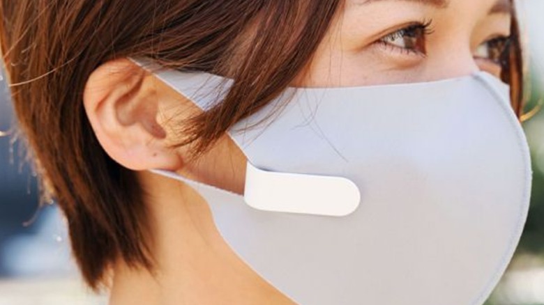 A woman wearing a facemask with an air fan attached