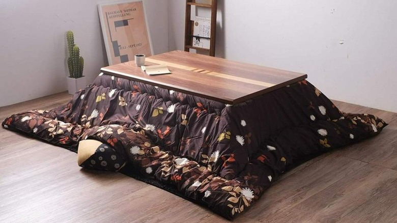 A Wooden Kotatsu Table Foot Heater in the corner of a white-walled room