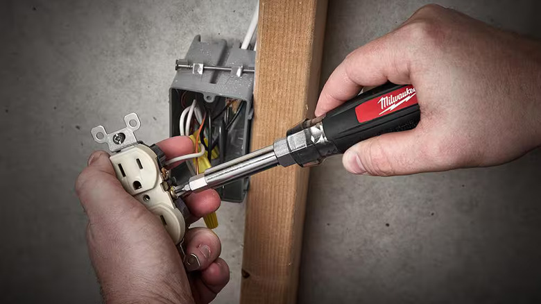 Electrician using a Milwaukee 13-in-1 screwdriver ito wire an electrical wall socket