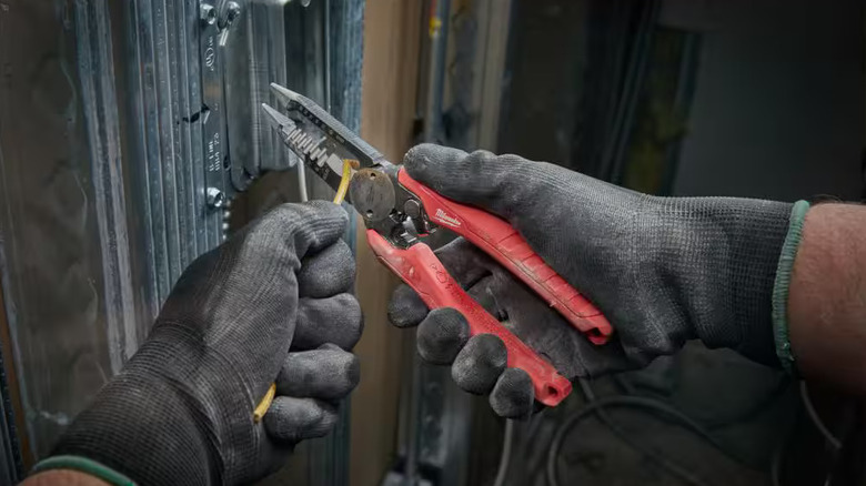 A worker wearing safety gloves using the Milwaukee 6-in-1 wire stripper/cutter on a wiring job