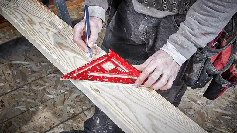 Professional using a Milwaukee rafter square on a piece of dimensional lumber